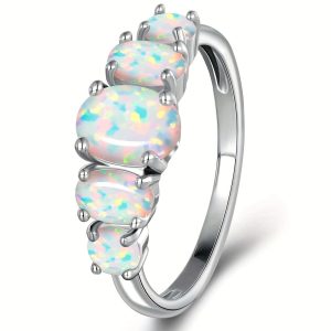 Close-up shot of an elegant oval white opal five-stone band ring in a polished silver setting